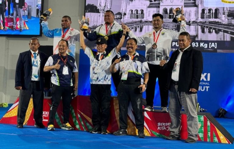 LIFTER Angkat Berat Jabar, Amir Hamzah diatas podium tersenyum bahagia saat berfoto bersama sang pelatih, Usdi Permana (kedua dari kiri depan) setelah meraih medali emas di kelasnya di Gedung PABBSI Komplek SHG Banda Aceh, Rabu (18/9/2024). (Foto: Ofisial/G-SPORTS.ID)