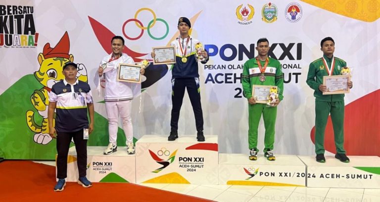 HUGGIES Yustisio naik ke podium juara dan berhak atas medali emas setelah berhasil memenangkan pertarungannya di nomor Kumite +84 kg putra cabang karate PON XXI/2024. (Foto: Ofisial Tim/G-SPORTS.ID)