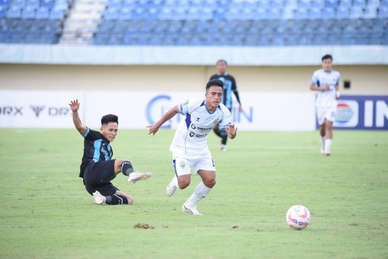 PEMAIN PSKC Cimahi (putih) melaju meski terkena hadangan pemain Persela (hijau) dalam pertandingan Babak 8 Besar Liga 2 yang berlangsung di Stadion si Jalak Harupat, Rabu (12/2/2025). (Foto: Arief K/G-SPORTS.ID)